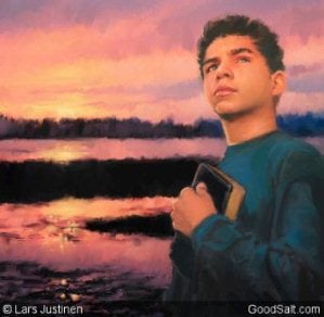 A teenage boy holding his bible with sunset behind him
