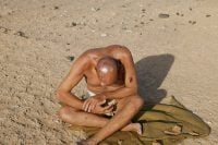 Naked man with injuries sitting in desert Job