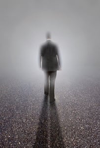 The silhouette of a man in a business suit headed towards a white light.
