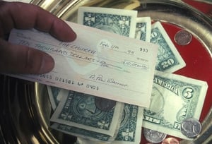 A man placing a check in the offering plate.