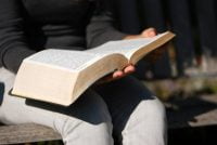 Woman sitting outside reading a Bible.