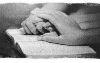 Folded Hands Resting on Bible