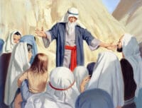 An elderly Moses is standing at the foot of a mountain in front of a crowd of people. His hands are outstretched and he appears to be talking to the crowd. S