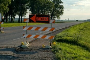 Roadside detour sign with arrow in rural Plainview, MN, under clear skies. Perfect for travel and road maintenance themes.